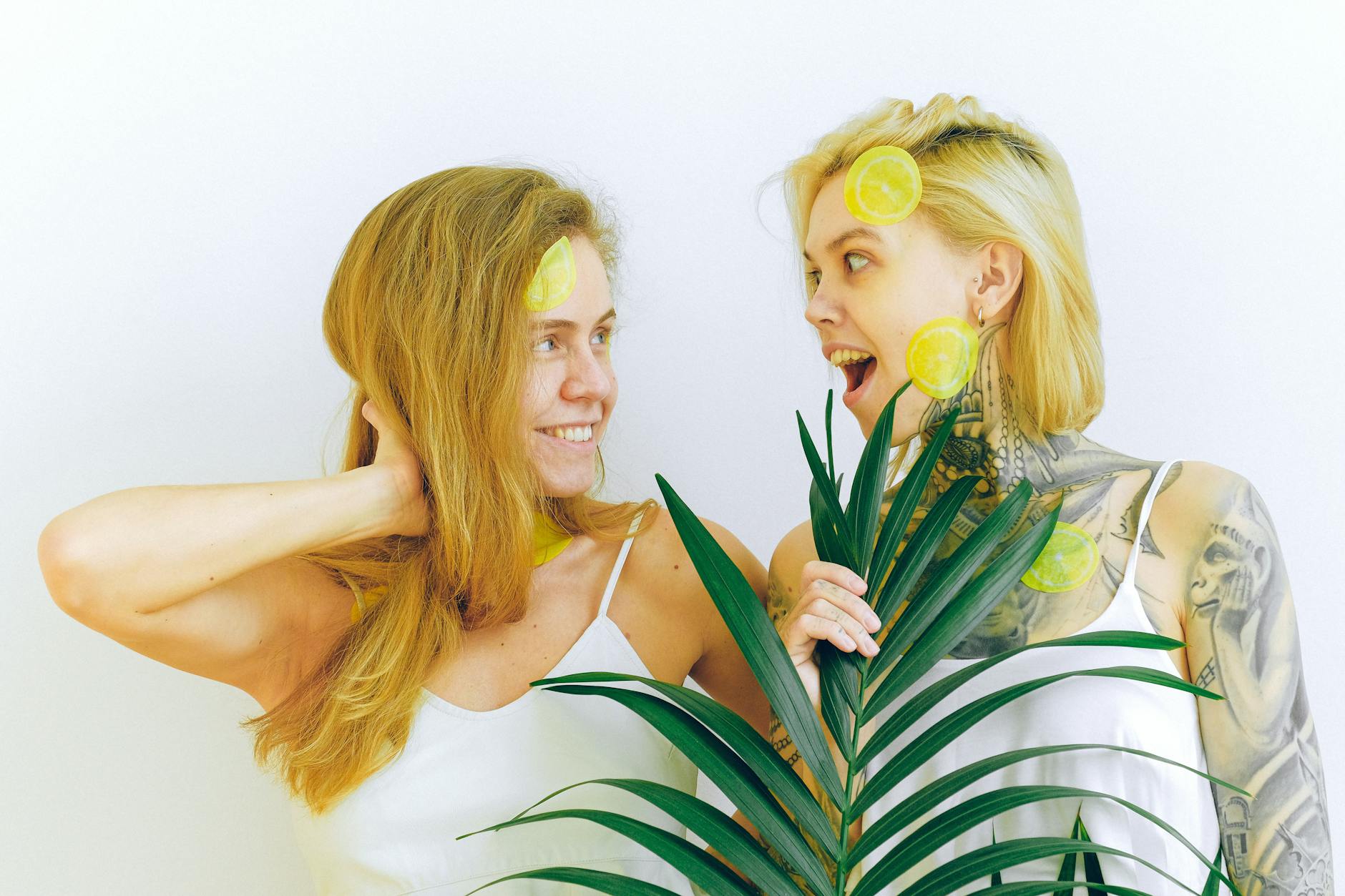 Two women smiling and holding lemon slices together, representing joy and sensuality during pleasure recovery