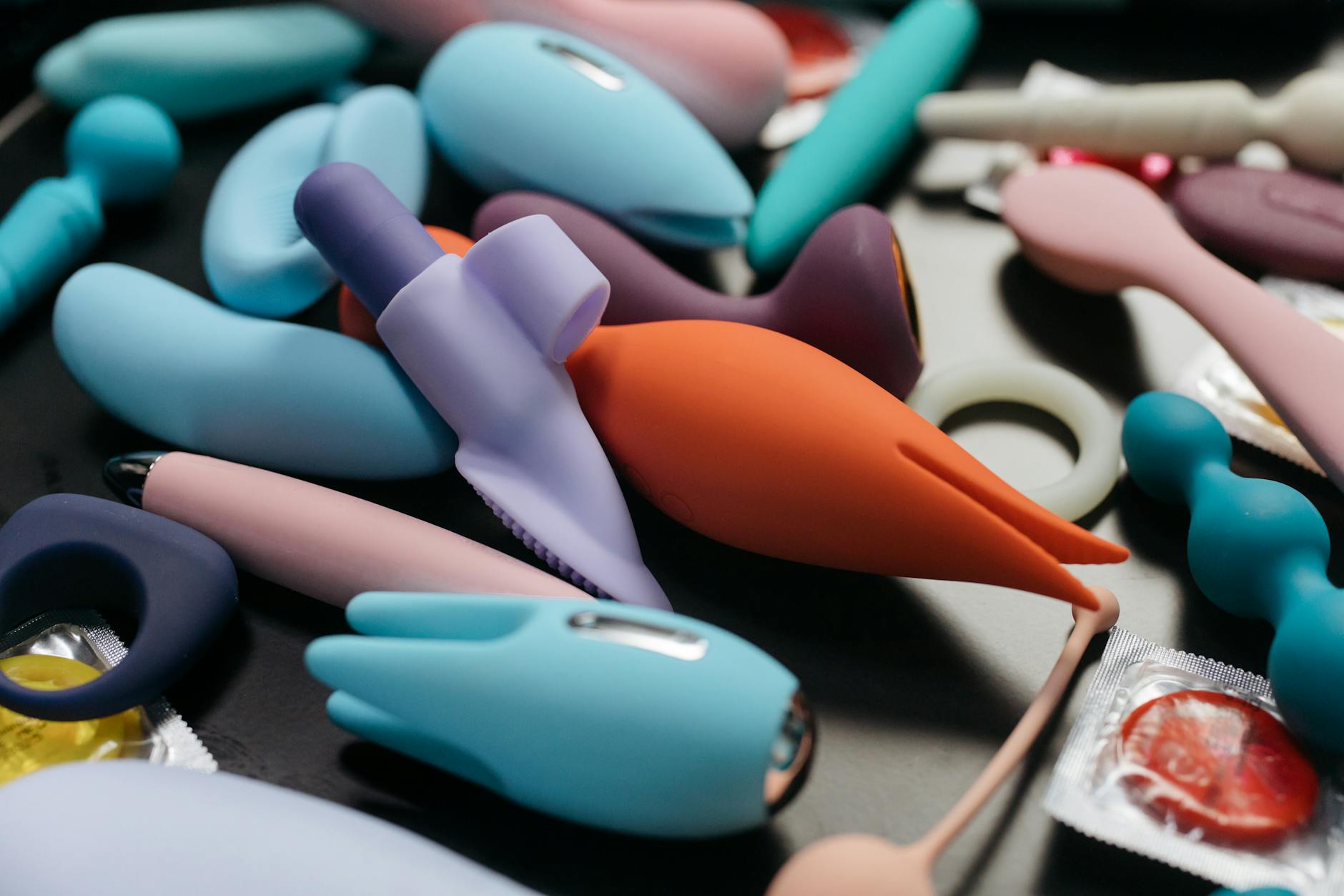 Woman holding blue and pink vibrators in a thoughtful, intentional pose