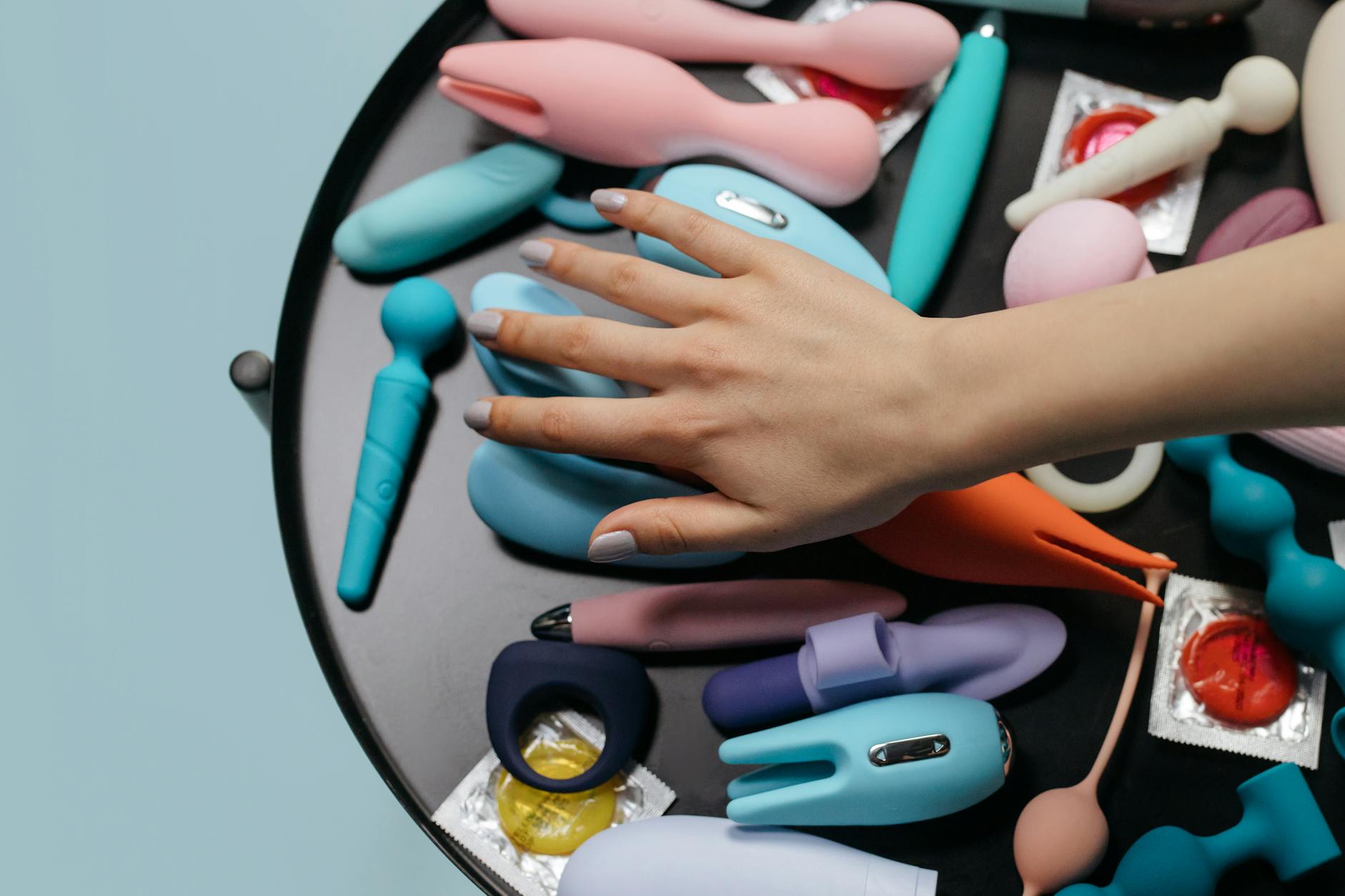 Eine Hand hält einen orangefarbenen Vibrator gegen einen minimalistischen lila Hintergrund und zeigt moderne Sinnlichkeit.