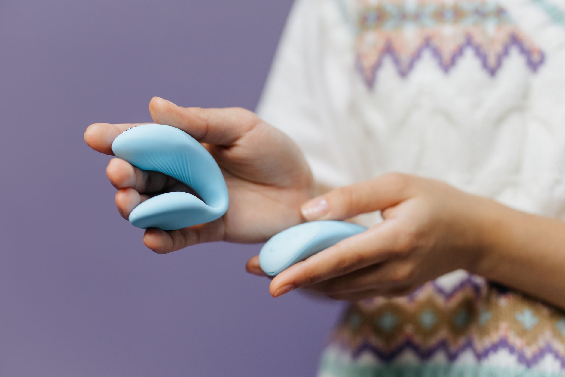 Close-up of hands holding a sleek lemon-colored vibrator against a soft background
